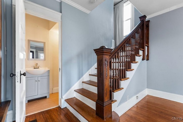 stairway featuring crown molding, sink, and hardwood / wood-style floors