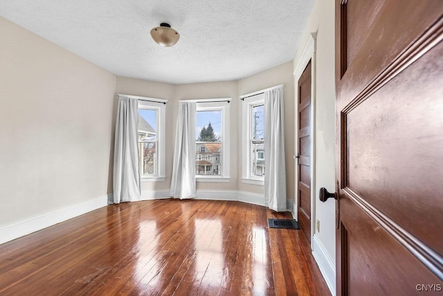 spare room featuring a textured ceiling and dark wood-type flooring