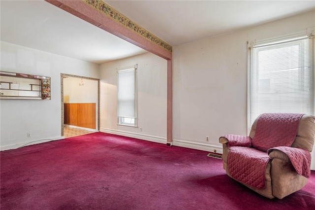 living area featuring beam ceiling and carpet floors