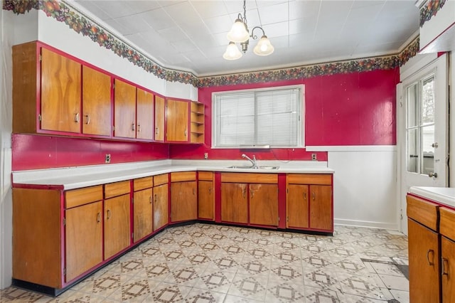 kitchen with a healthy amount of sunlight, ornamental molding, sink, and an inviting chandelier