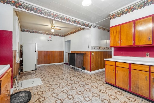 kitchen featuring wood walls, ceiling fan, white refrigerator, and crown molding