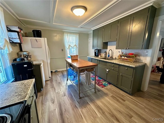 kitchen with light stone countertops, sink, green cabinets, light hardwood / wood-style floors, and range