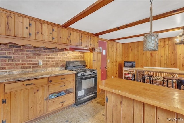 kitchen featuring wood walls, black appliances, hanging light fixtures, beamed ceiling, and butcher block counters