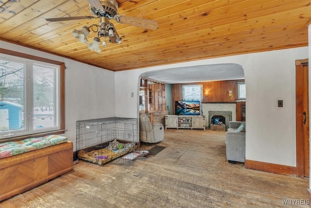 interior space with wood walls, ceiling fan, ornamental molding, and wood ceiling