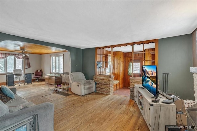 living room featuring light hardwood / wood-style flooring, ceiling fan, and a stone fireplace