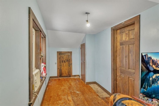 hallway featuring a wall mounted air conditioner, light hardwood / wood-style floors, and vaulted ceiling