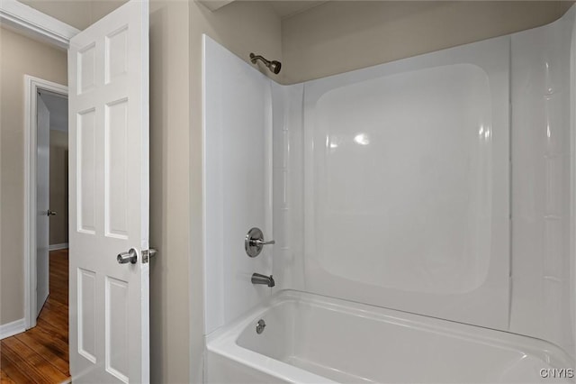 bathroom with washtub / shower combination and hardwood / wood-style floors