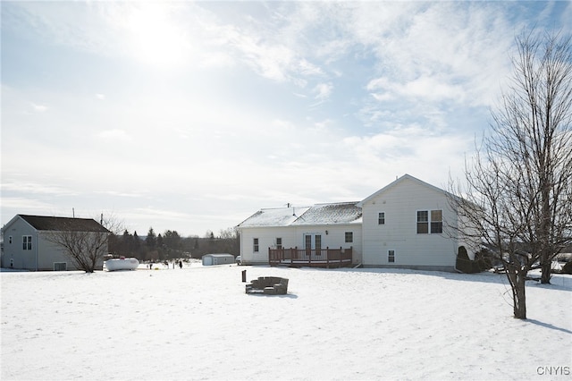 snow covered house featuring a deck and an outdoor structure