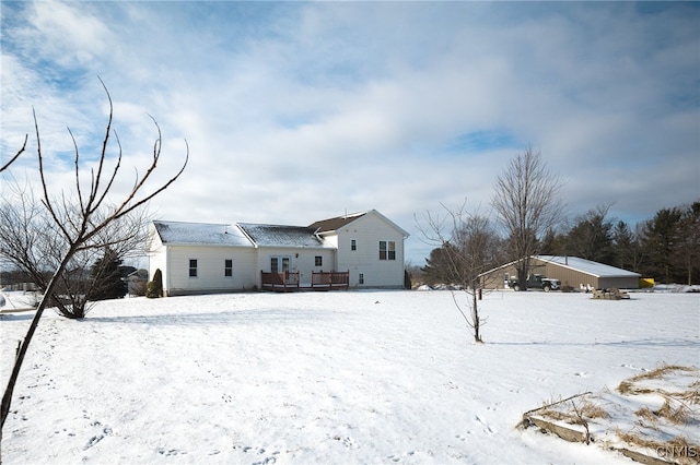 snow covered back of property featuring a deck