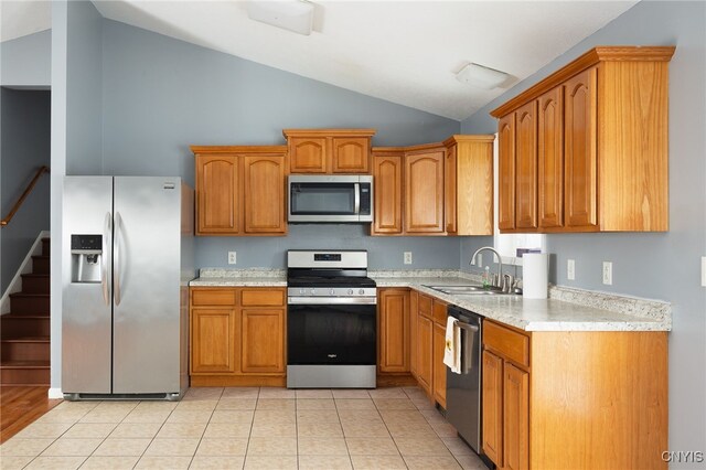 kitchen featuring light countertops, appliances with stainless steel finishes, brown cabinetry, and a sink