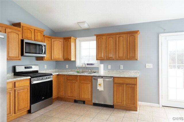 kitchen featuring lofted ceiling, light tile patterned flooring, stainless steel appliances, a sink, and visible vents