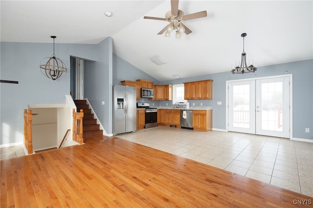 kitchen featuring light wood finished floors, appliances with stainless steel finishes, light countertops, pendant lighting, and a sink