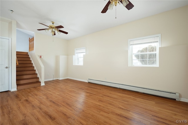 empty room with baseboards, stairway, baseboard heating, and wood finished floors