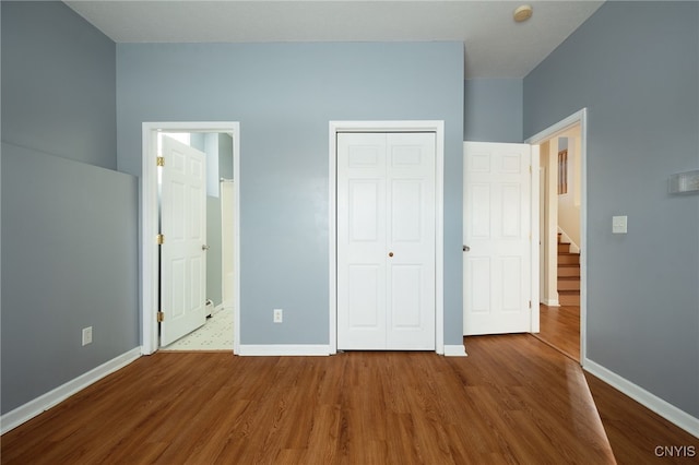 unfurnished bedroom with a closet, baseboards, and wood finished floors