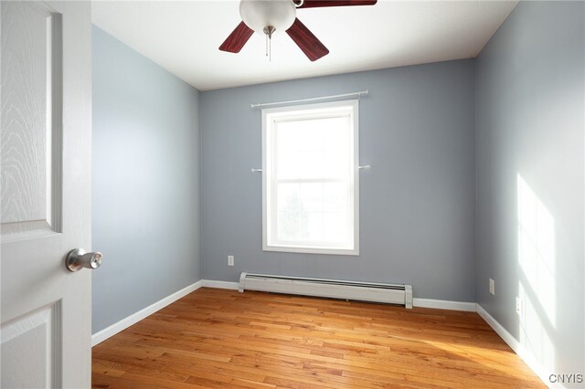 unfurnished room with a baseboard heating unit, light wood-style floors, baseboards, and ceiling fan