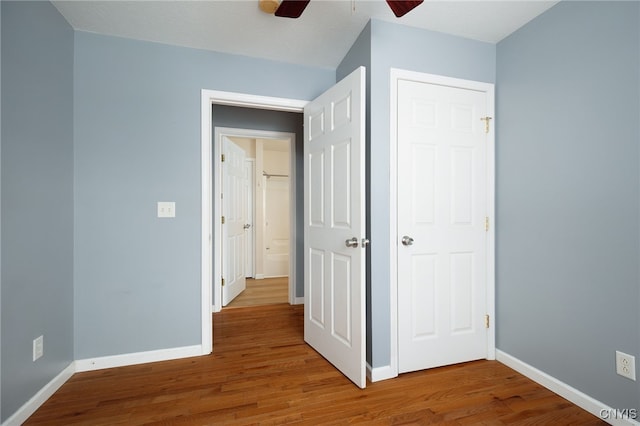 unfurnished bedroom with a ceiling fan, a closet, baseboards, and wood finished floors