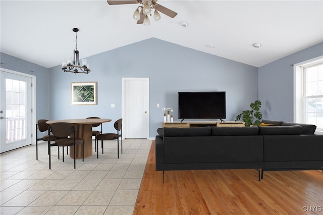 living area with ceiling fan with notable chandelier, lofted ceiling, and light tile patterned floors