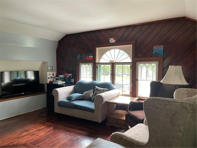 living room featuring dark hardwood / wood-style floors, wood walls, and lofted ceiling