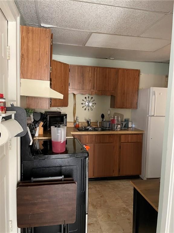 kitchen featuring a paneled ceiling, custom range hood, sink, electric range, and white refrigerator