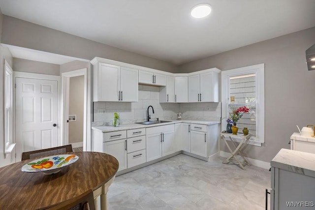 kitchen with decorative backsplash, white cabinetry, and sink