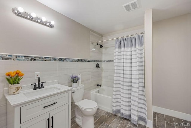 full bathroom with vanity, toilet, tile walls, and shower / tub combo with curtain