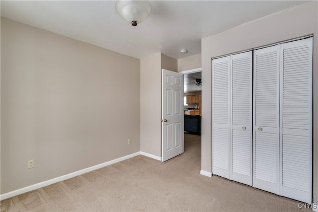 unfurnished bedroom with light colored carpet and a closet