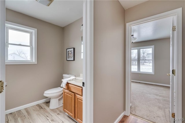 bathroom with vanity, a healthy amount of sunlight, toilet, and wood-type flooring