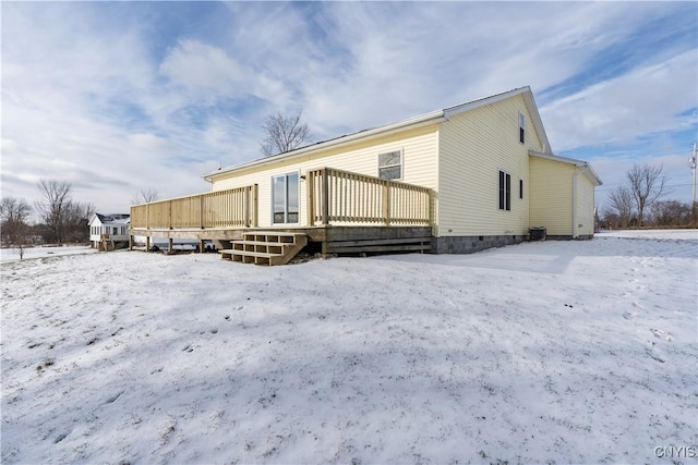 snow covered back of property with a deck