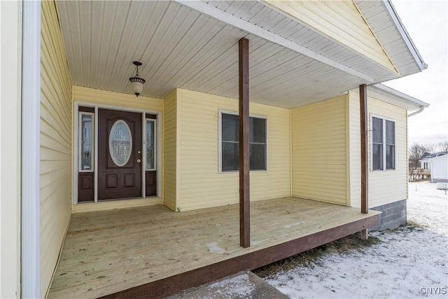 snow covered property entrance with a porch