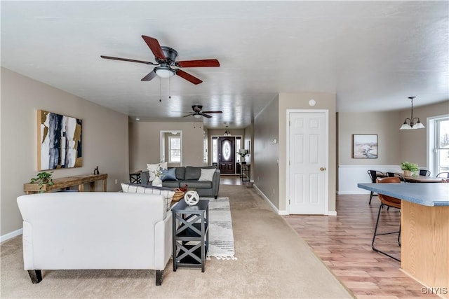 living room featuring ceiling fan with notable chandelier and light wood-type flooring