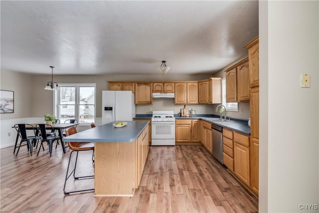 kitchen featuring white appliances, sink, light wood-type flooring, decorative light fixtures, and a kitchen island