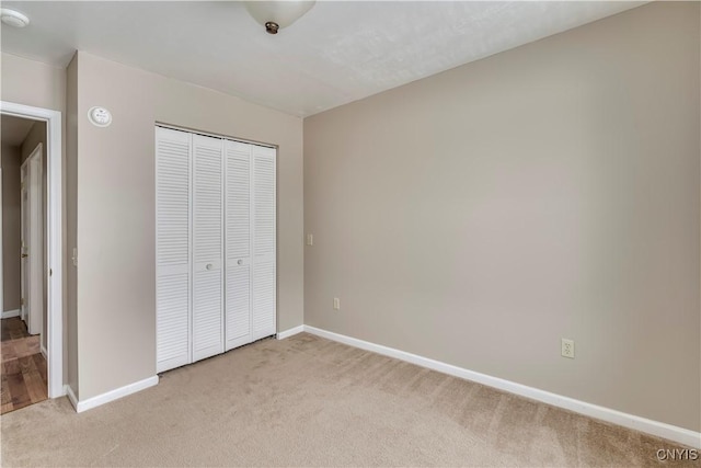 unfurnished bedroom featuring light colored carpet and a closet