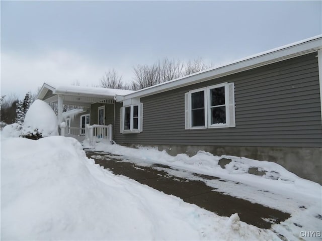 view of snowy exterior featuring a porch