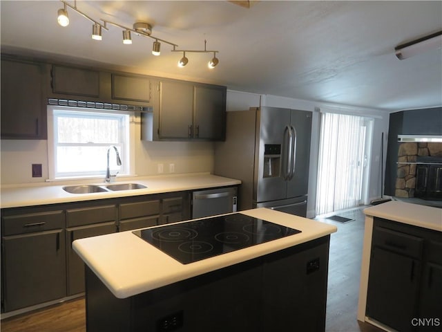 kitchen featuring hardwood / wood-style flooring, a center island, sink, stainless steel appliances, and a stone fireplace