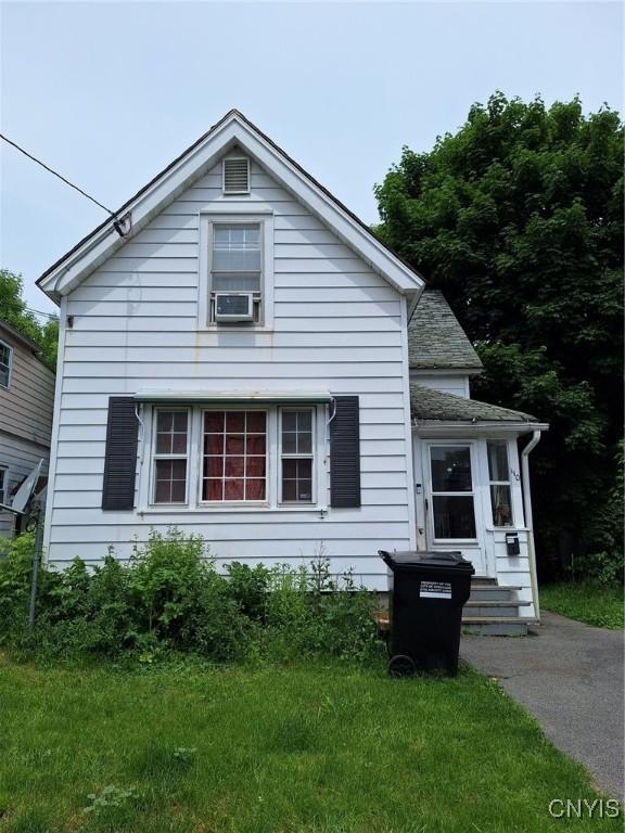 bungalow-style home with cooling unit and a front yard