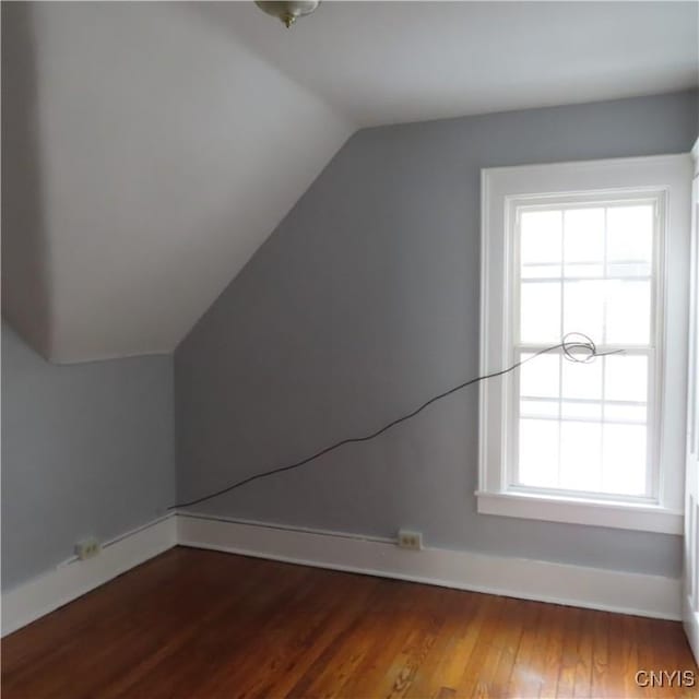 additional living space featuring vaulted ceiling and dark wood-type flooring