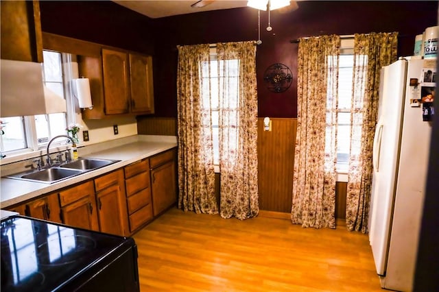 kitchen featuring light wood-type flooring, electric range oven, ceiling fan, sink, and white refrigerator