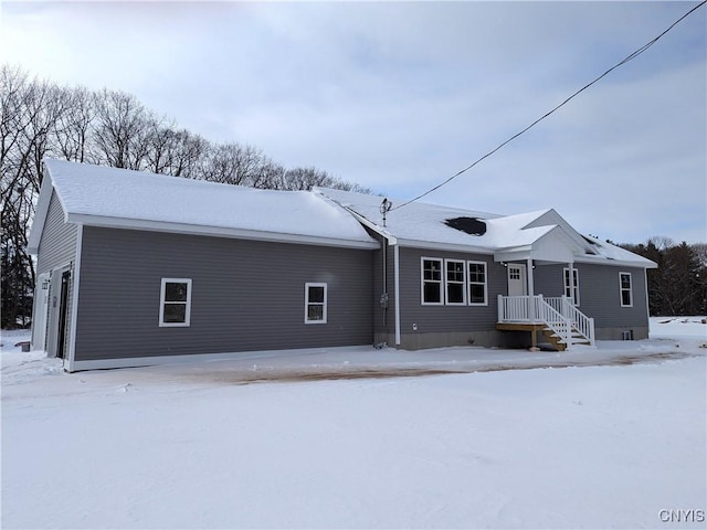 snow covered rear of property with a garage