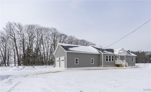 snow covered rear of property with a garage