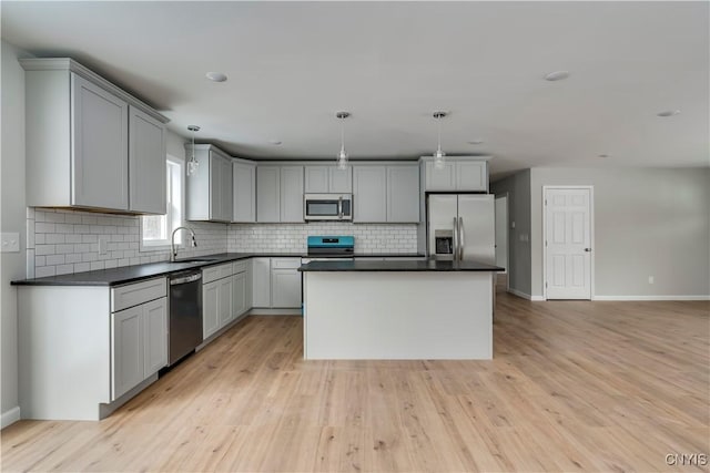 kitchen with sink, stainless steel appliances, pendant lighting, gray cabinets, and a kitchen island