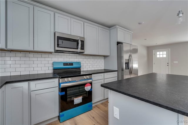 6661 Pine Grove Rd, Watson, NY 13343 - kitchen featuring appliances with stainless steel finishes, dark countertops, light wood-type flooring, and decorative backsplash