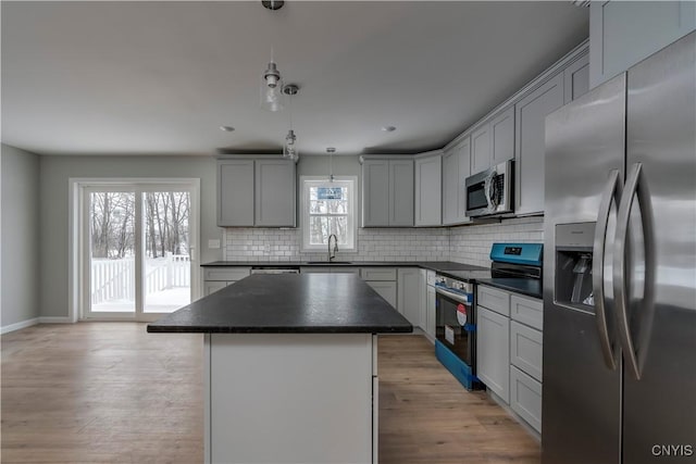 kitchen featuring gray cabinets, a kitchen island, stainless steel appliances, and decorative light fixtures