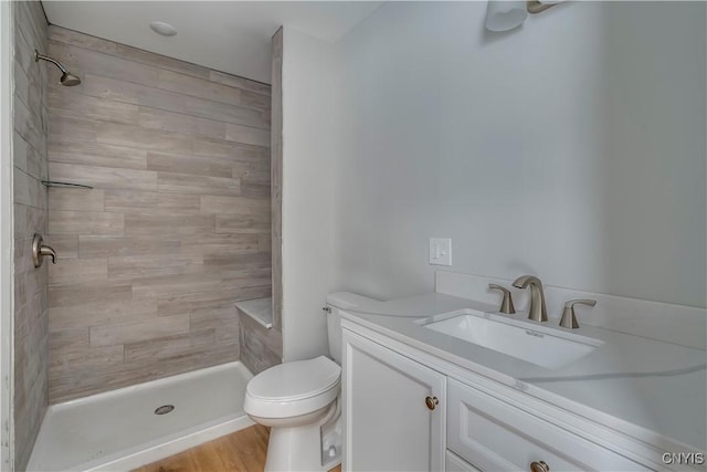 bathroom featuring vanity, toilet, and a tile shower