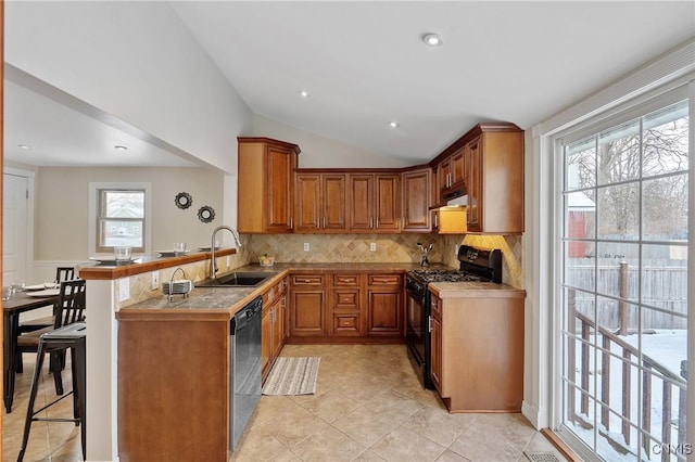 kitchen with kitchen peninsula, a kitchen bar, vaulted ceiling, sink, and black appliances