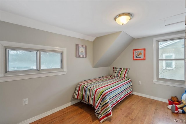 bedroom featuring lofted ceiling, light wood-type flooring, and multiple windows