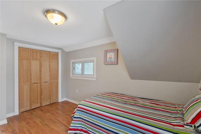 bedroom with lofted ceiling, light wood-type flooring, and a closet