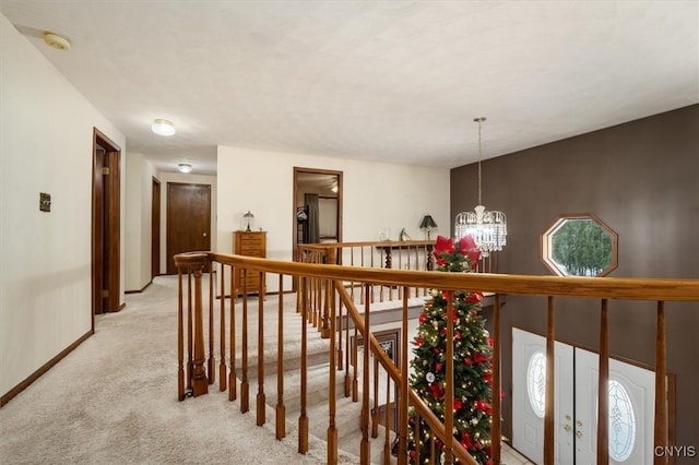 hall with light carpet and an inviting chandelier