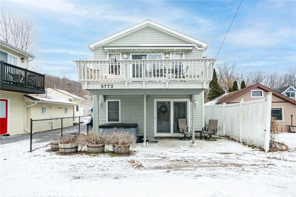 snow covered rear of property featuring a balcony