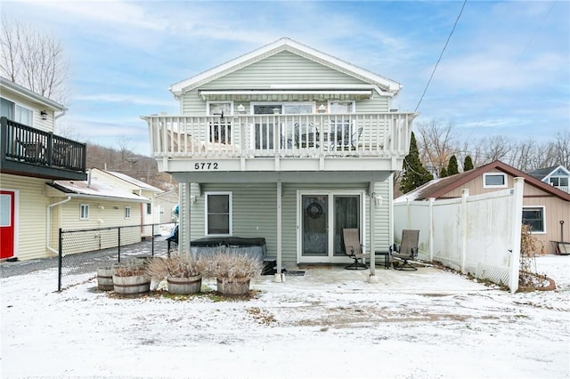 snow covered rear of property featuring a balcony