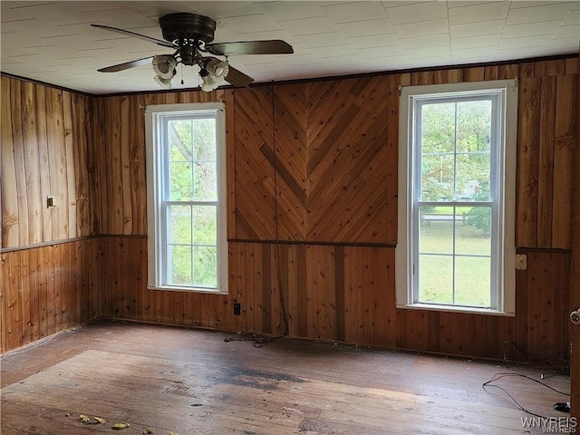 empty room featuring ceiling fan, hardwood / wood-style floors, and wood walls